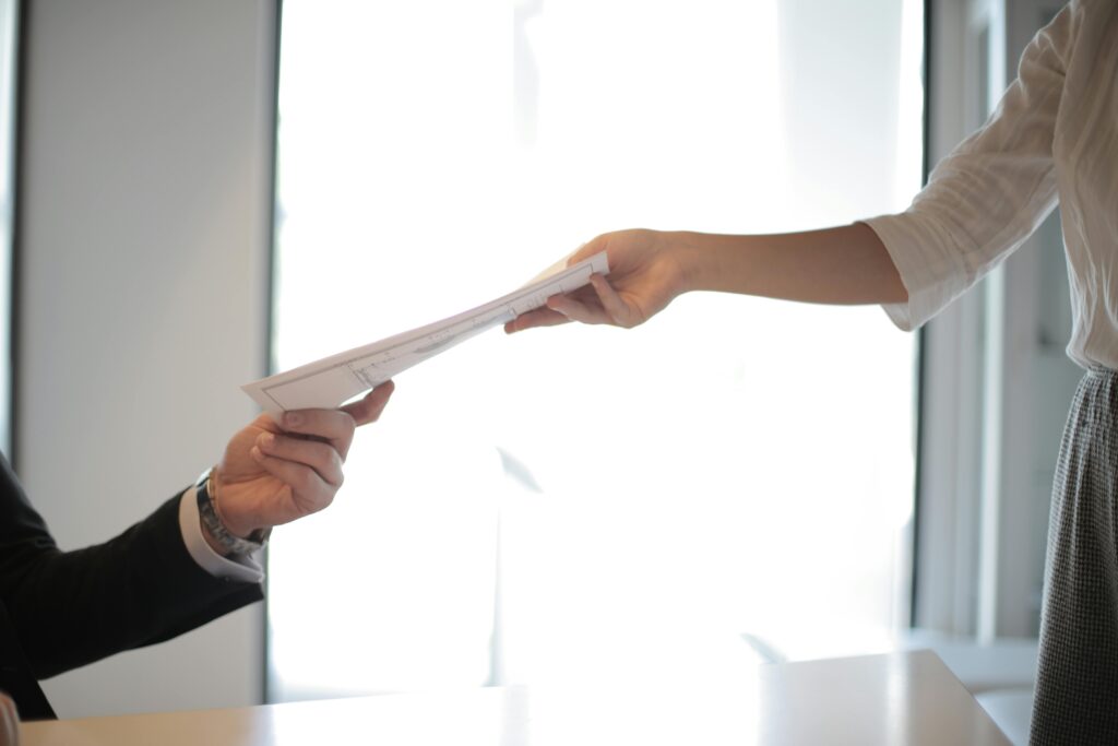 persona recibiendo un currículum vitae profesional en la mano